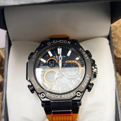 A G-Shock analog-digital watch with a black case, gray dial, and bright orange strap, presented inside its white gift box.