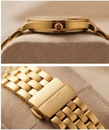 Gold-tone stainless steel watch band and case shown in two close-up views on a beige textured display cushion. The top view shows the side profile of the watch case with crown, and the bottom view shows the link bracelet clasp with an engraved wing logo.